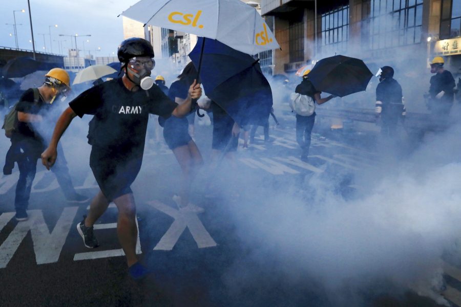 Demonstranter i Hongkong skyddar sig från polisens tårgas med hjälp av paraplyer.
