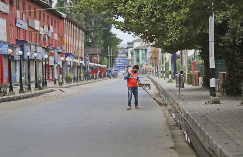 En arbetare städar gatan i staden Srinagar i Indienkontrollerade Kashmir under utegångsförbudet.