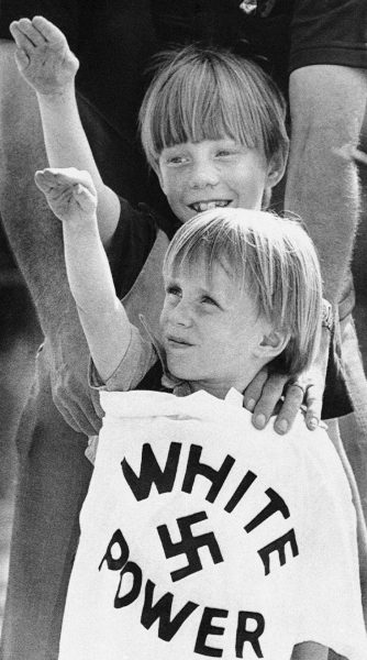 Två barn höjer sina händer vid ett Ku Klux Klan-möte 1980.