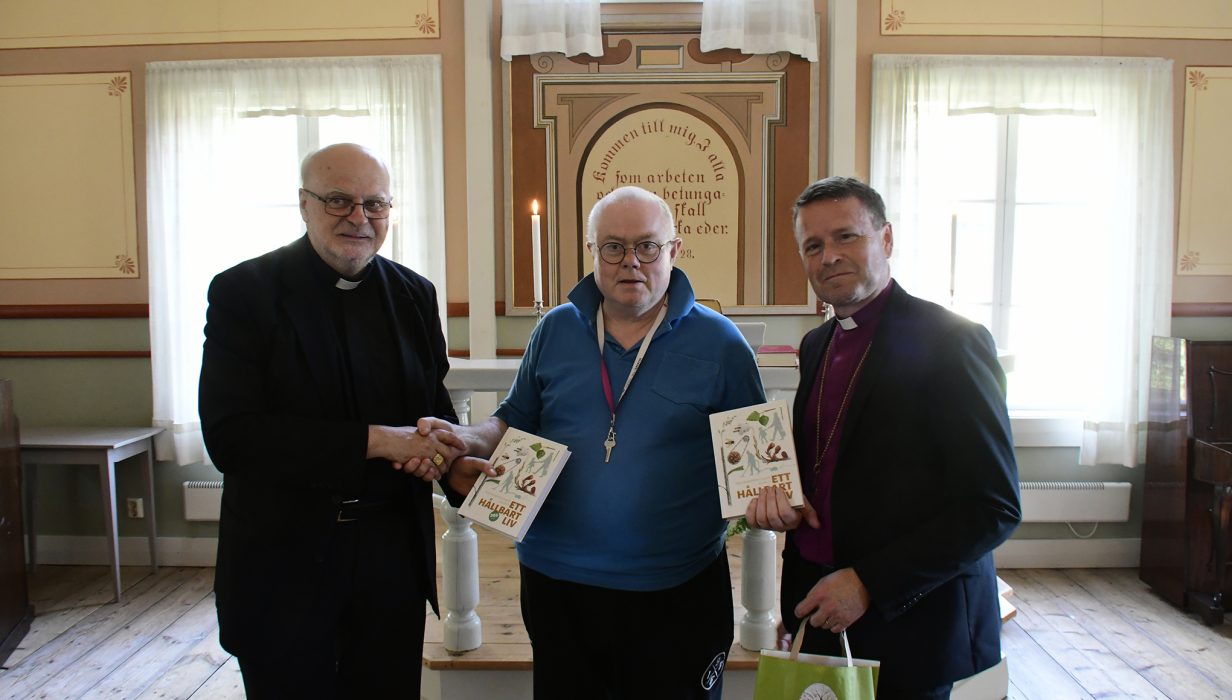 Hans Mannefred (i mitten) slår ett slag för mer ekologi i kyrkan genom att överlämna en bok i ämnet till biskop Sören Dalevi, Svenska kyrkan och kardinalen Anders Arborelius, Katolska kyrkan.