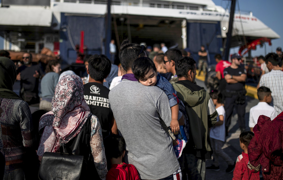 Barnfamiljer trängs med tillhörigheter hastigt nedpackade i sopsäckar vid hamnen på Lesbos.