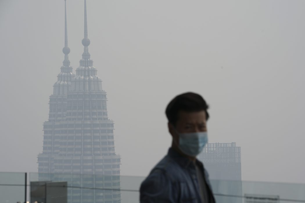 En turist i Kuala Lumpur med munskydd som skydd mot röken som väller in från skogsbränderna i grannlandet.