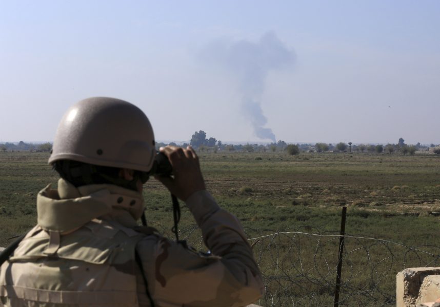 En irakisk soldat riktar kikaren mot en rökpelare efter ett flyganfall mot Islamiska staten (IS), vid gränsen mot Syrien.
