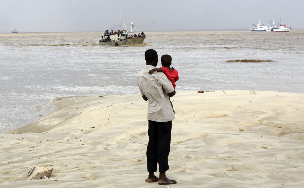 En man väntar på en båt med räddade människor från översvämmade områden i Mocambique.