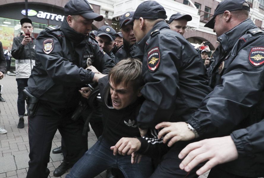 Poliser griper en demonstrant vid protester i Moskva 17 augusti.