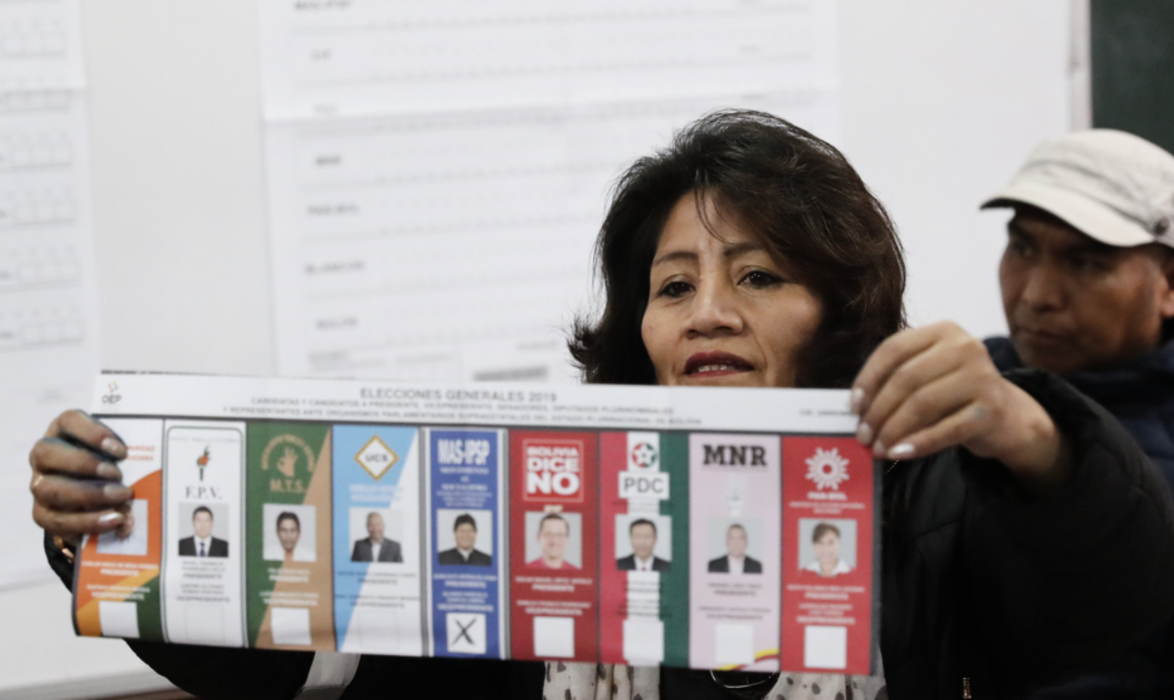 En vallokalsarbetare i La Paz, Bolivia, håller upp en röstsedel med ett kryss för den sittande presidenten Evo Morales.