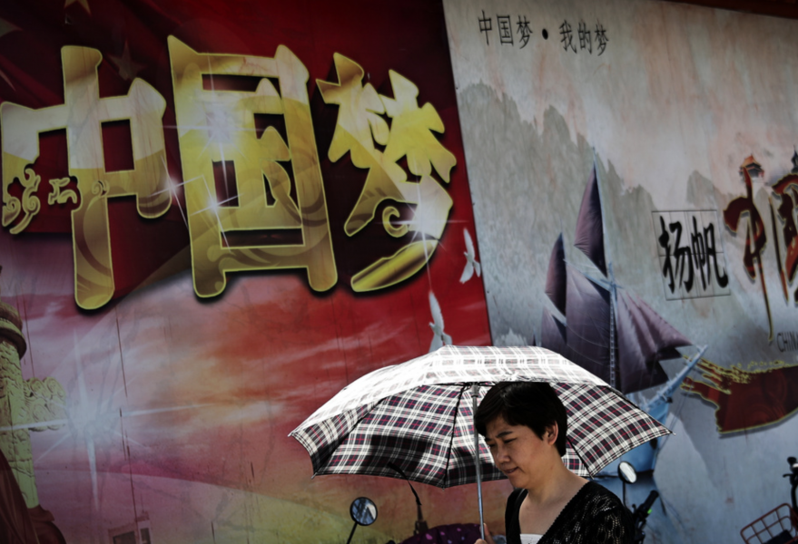 En kvinna går förbi ett propagandaplakat från Kommunistpartiet i Peking.
