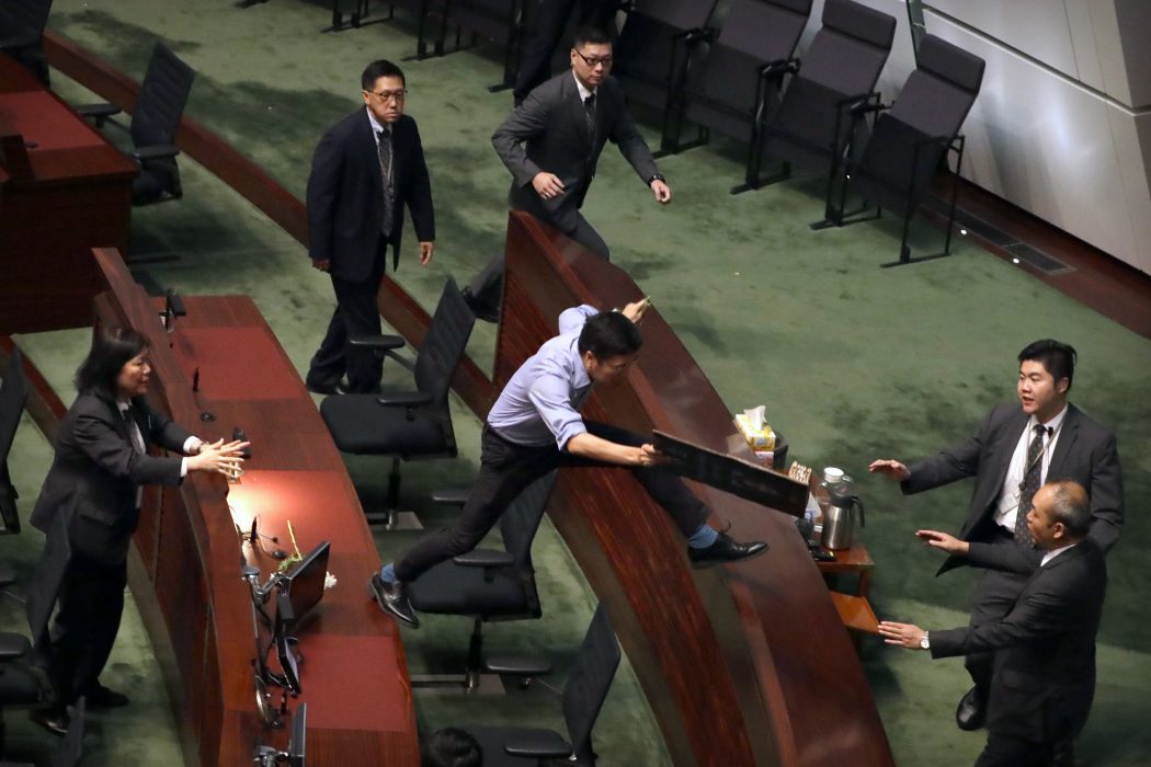 Vakter försöker få tag i ledamoten Au Nok-Hin som protesterade i parlamentet i Hongkong.