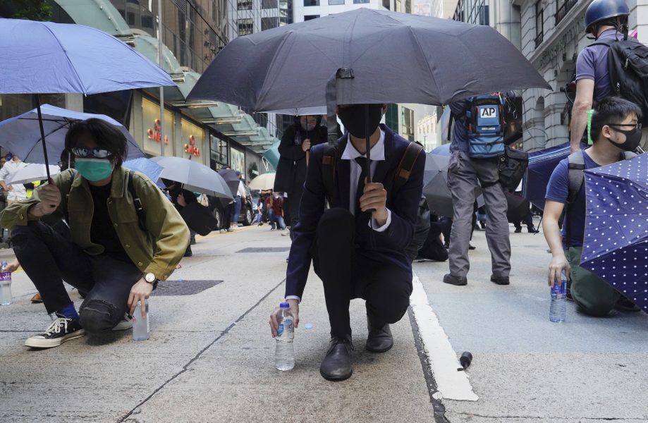 Demonstranter med paraplyer som skydd mot tårgas, och vattenflaskor att skölja ögonen från tårgas.