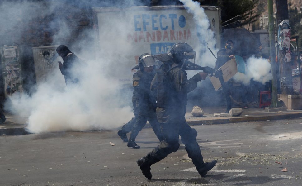 Polis skjuter tårgas för att hålla isär grupper av regeringskritiska respektive regeringsvänliga demonstranter under protester i Bolivias huvudstad La Paz i måndags.