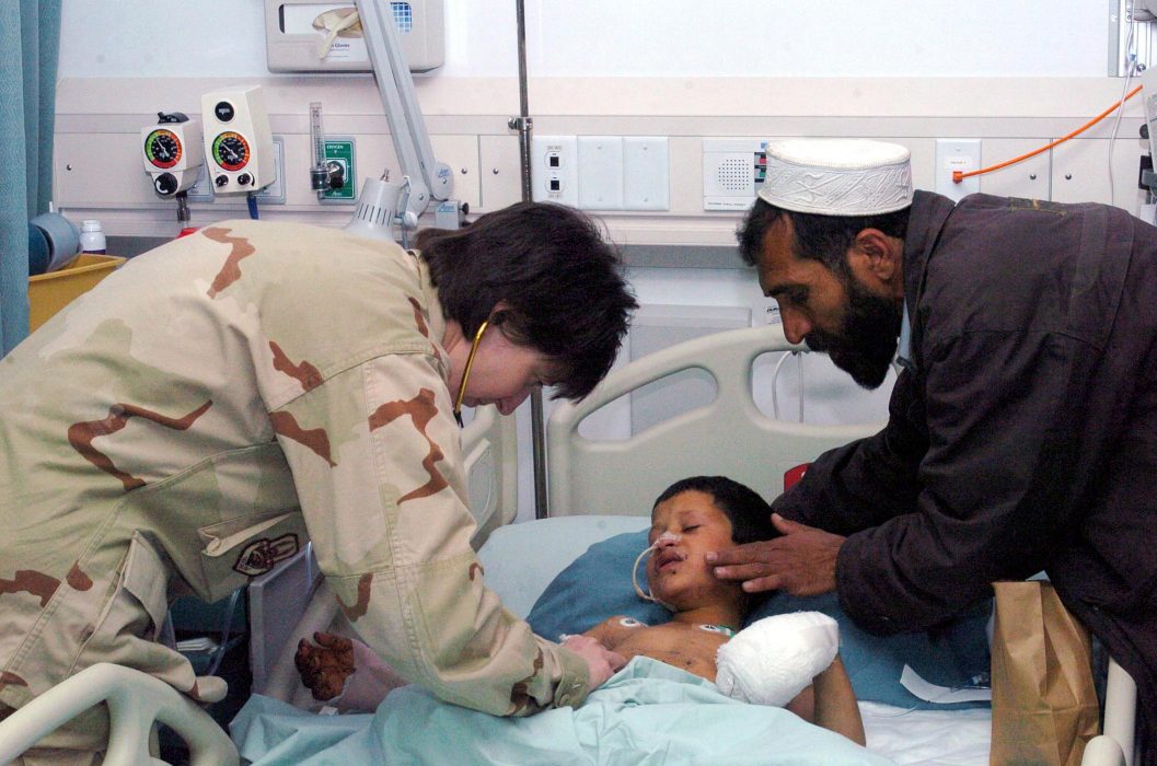 Åtta år gamla Orpan undersöks medan hans far tröstar honompå en amerikansk flygbas i Afghanistan.