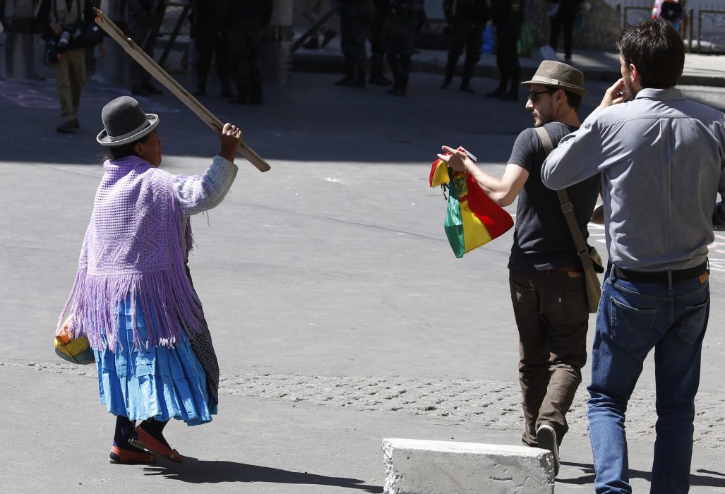 En kvinna som stödjer Evo Morales viftar ilsket mot några män som demonstrerar mot presidenten.