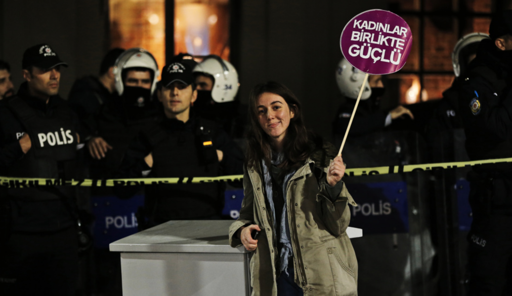 En demonstrant i Istanbul står med ett plakat där det står "Kvinnor är starka tillsammans".