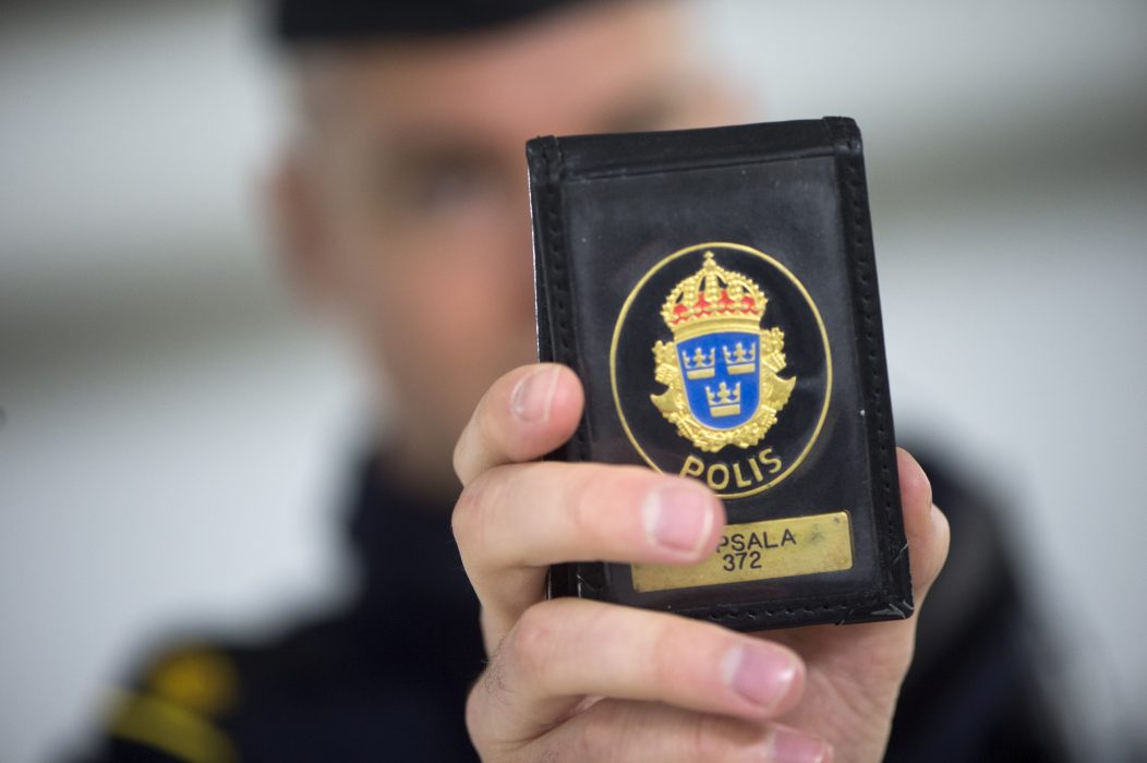 En polis visar upp ena halvan av sin polislegitimation.