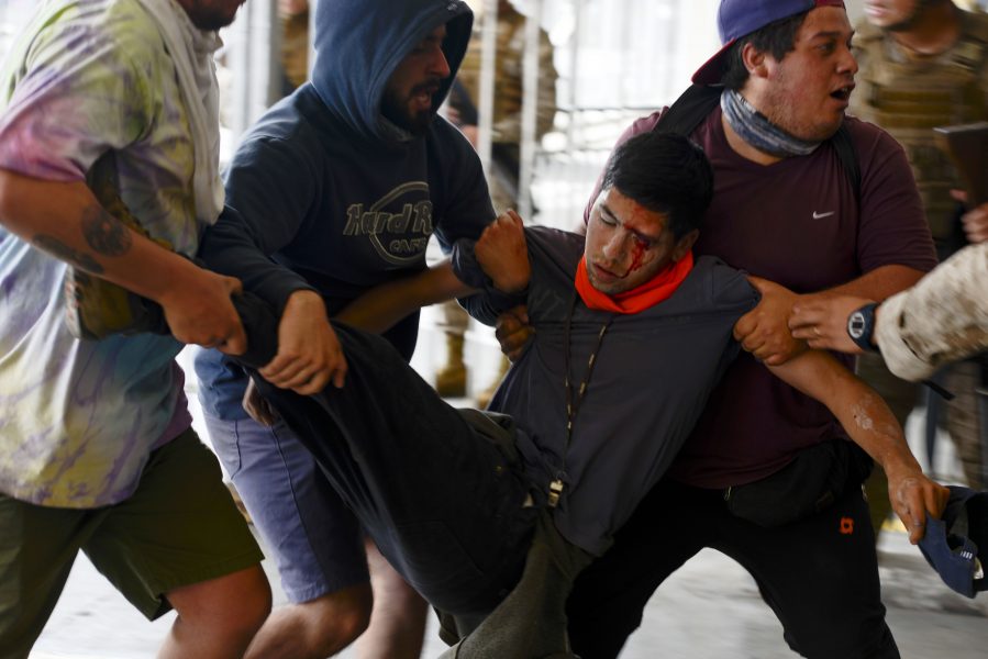 Ögonskadad demonstrant bärs iväg efter protester i Valparaiso, 25 oktober.