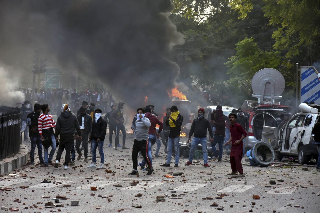 Människor kastar sten mot polisen i Lucknow på torsdagen.