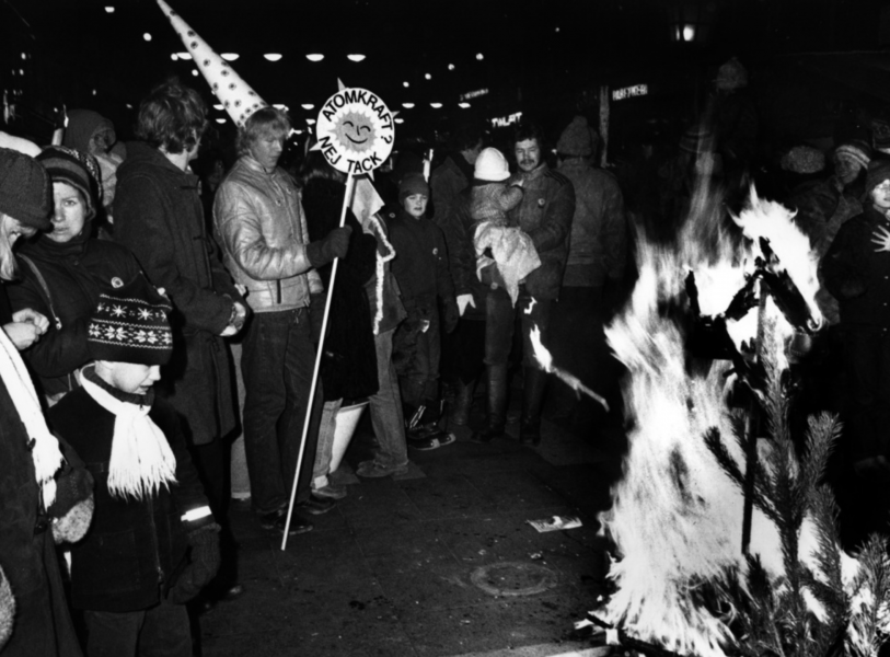 En demonstrant med stjärngossestrut på huvudet värmer sig vid en eld i samband med luciatåget mot kärnkraft i Stockholm, där omkring 15 000 personer deltog.