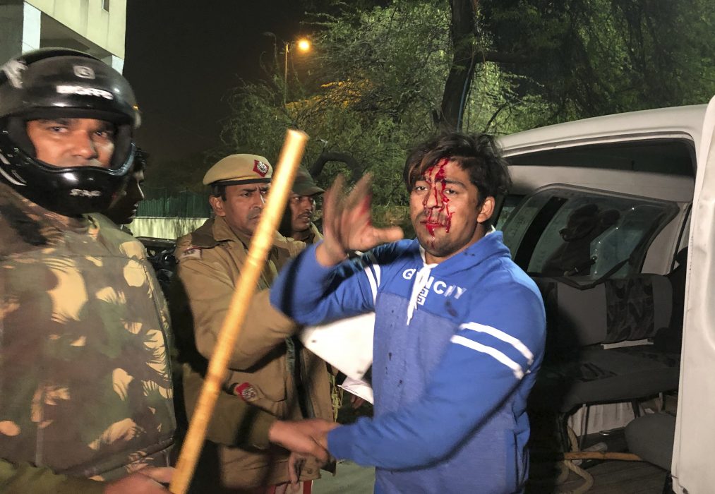 Polis griper en skadad student utanför universitetet Jamia Millia Islamia i Delhi, Indien.