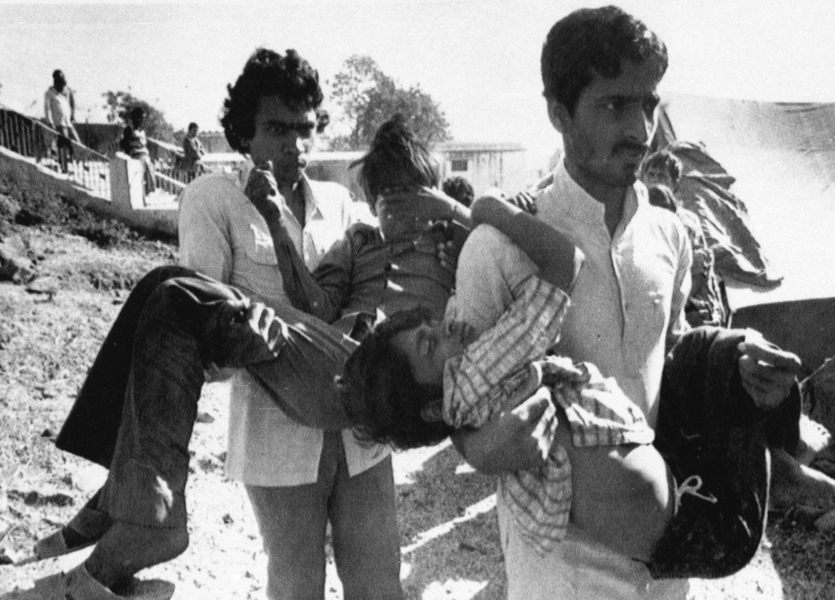 Två män bär på pojkar som har skadat ögonen vid gasutsläppet från fabriken i Bhopal, Indien, för 35 år sedan, 1984.