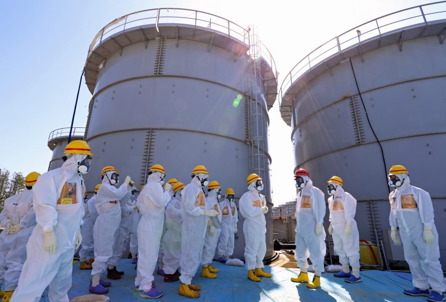 En av tusentals behållare av förorenat vatten vid Fukushimas kärnkraftverk i Japan (här med Japans premiärminister Shinzo Abe, röd hjälm).