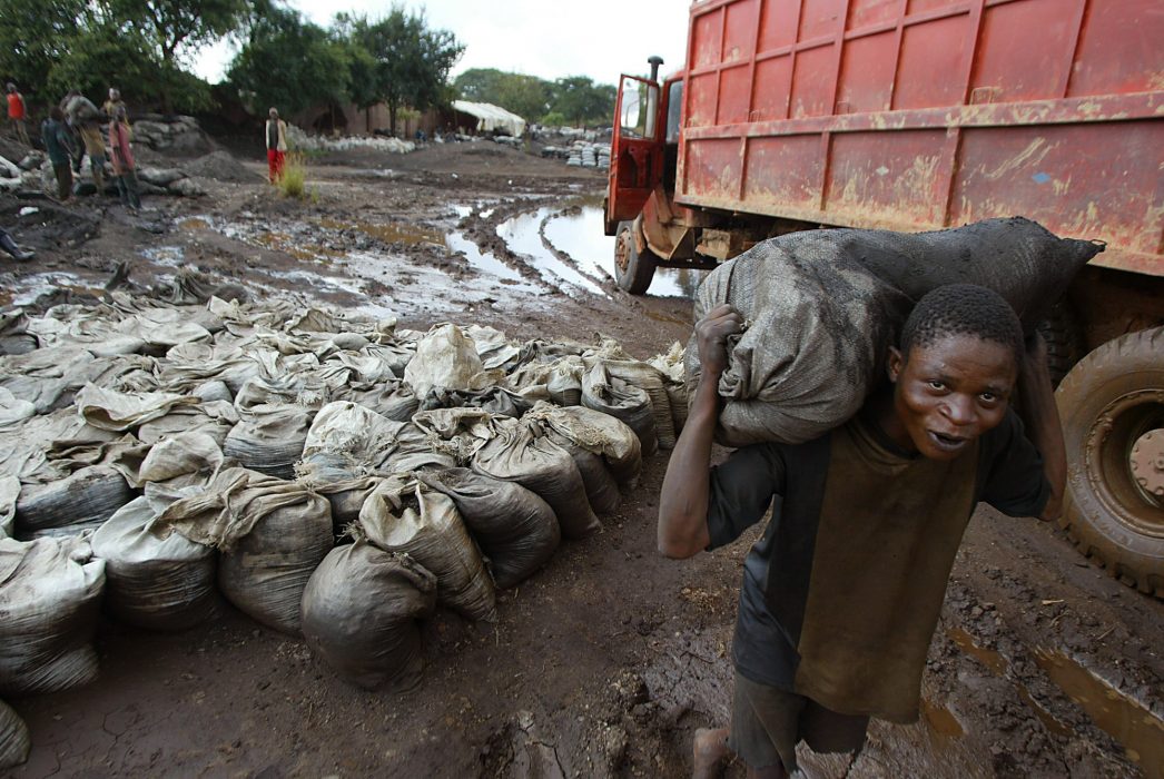 En ung man bär på en säck med blöt kobolt vid en urangruva i Kongo-Kinshasa.