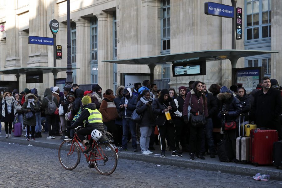 En kvinna cyklar förbi en kö till en buss vid Gare du Nord i Paris.