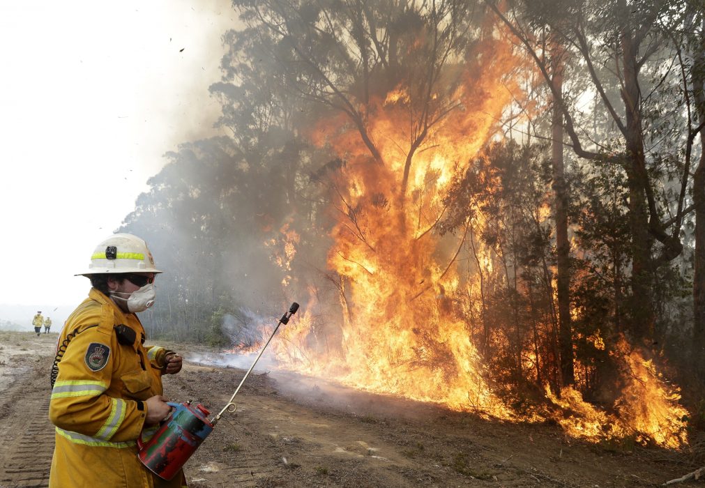 En brandman tänder under torsdagen en kontrollerad brand nära Tomerong, New South Wales i Australien, i ett försök att begränsa en närliggande brand.
