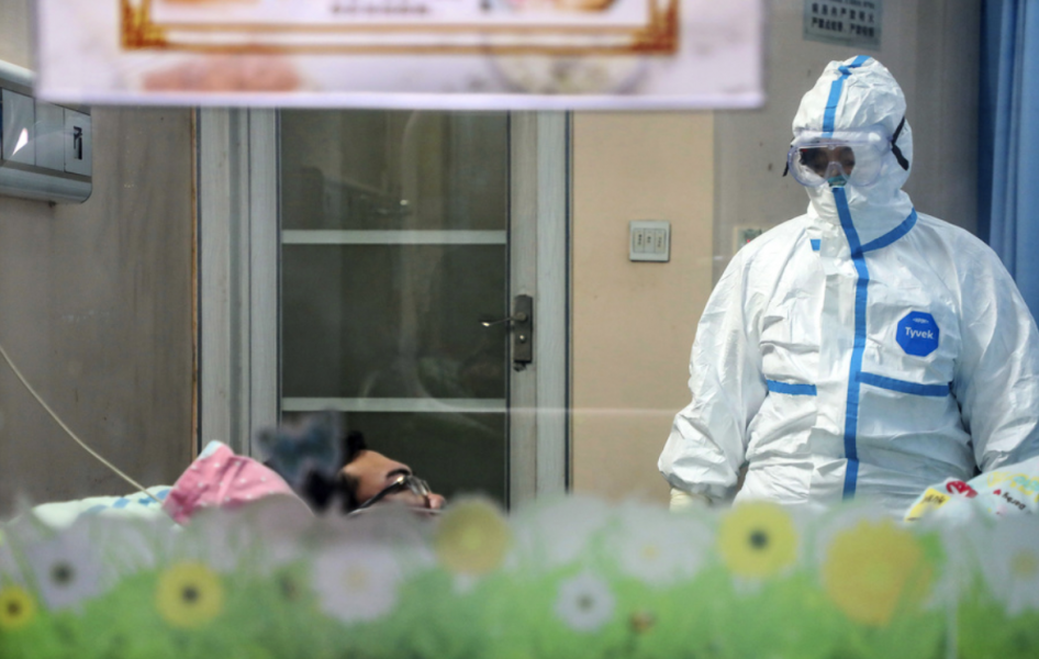 En läkare undersöker en patient i ett isoleringsrum ett sjukhus i Wuhan.
