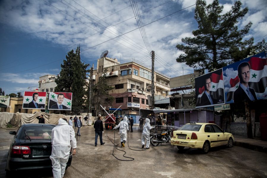 Sjukhuspersonal desinfekterar och städar utanför ett sjukhus i Qamishli, i nordöstra Syrien på gränsen mot Turkiet.