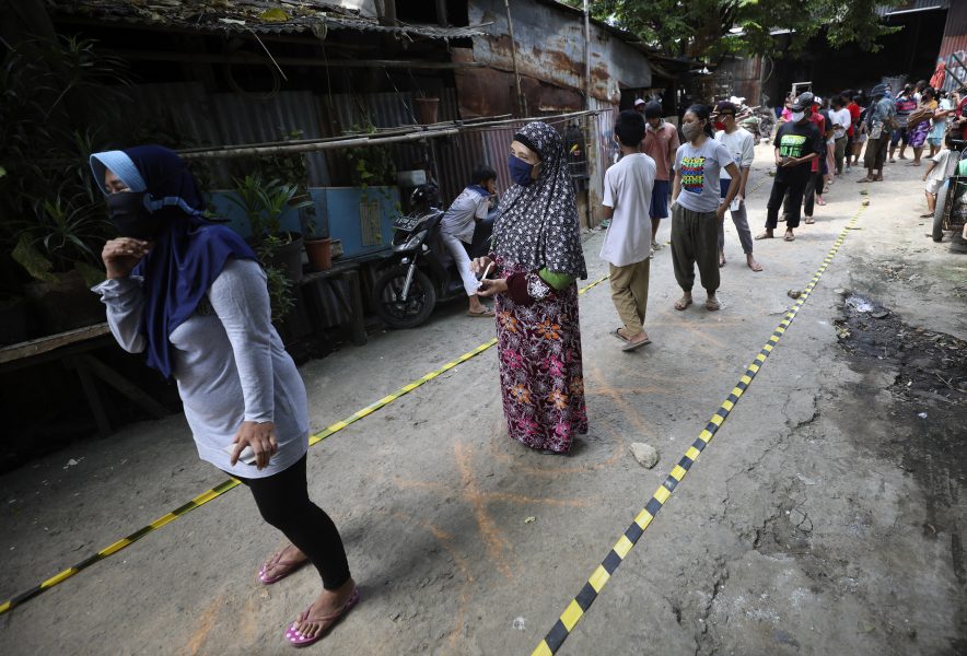 Fattiga indoneser håller avståndet när de köar för mat i ett slumområde i Jakarta.