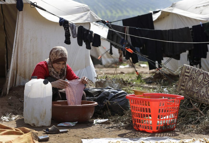 En kvinna tvättar kläder utanför sitt tält i ett flyktingläger i staden Atmeh i norra Syrien.