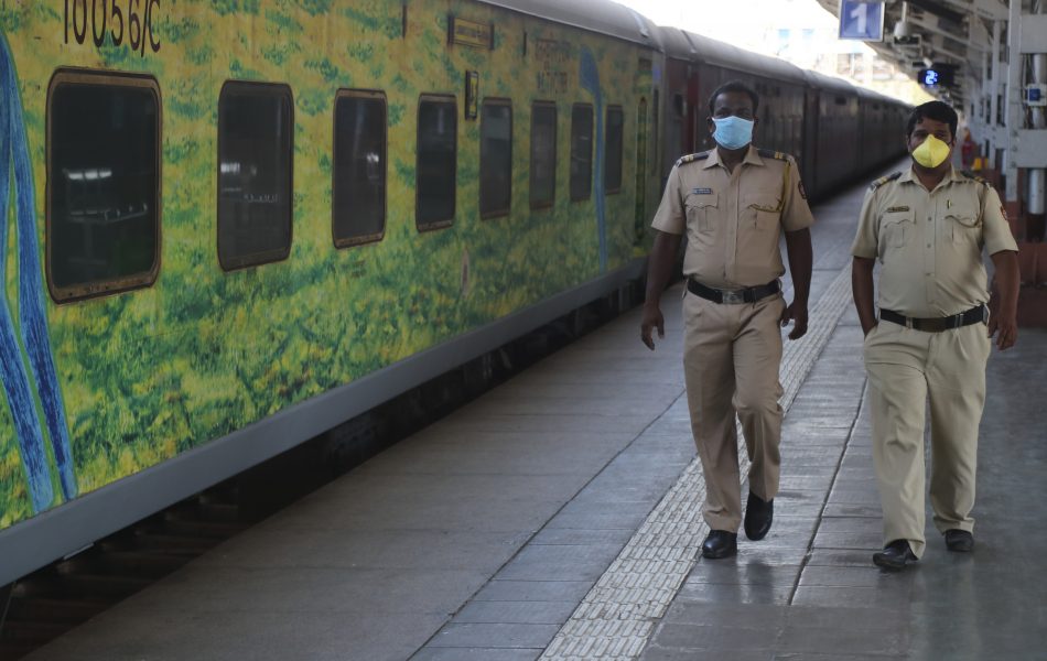 Poliser i munskydd inspekterar en tom tågperrong i Bombay (Mumbai) i Indien.