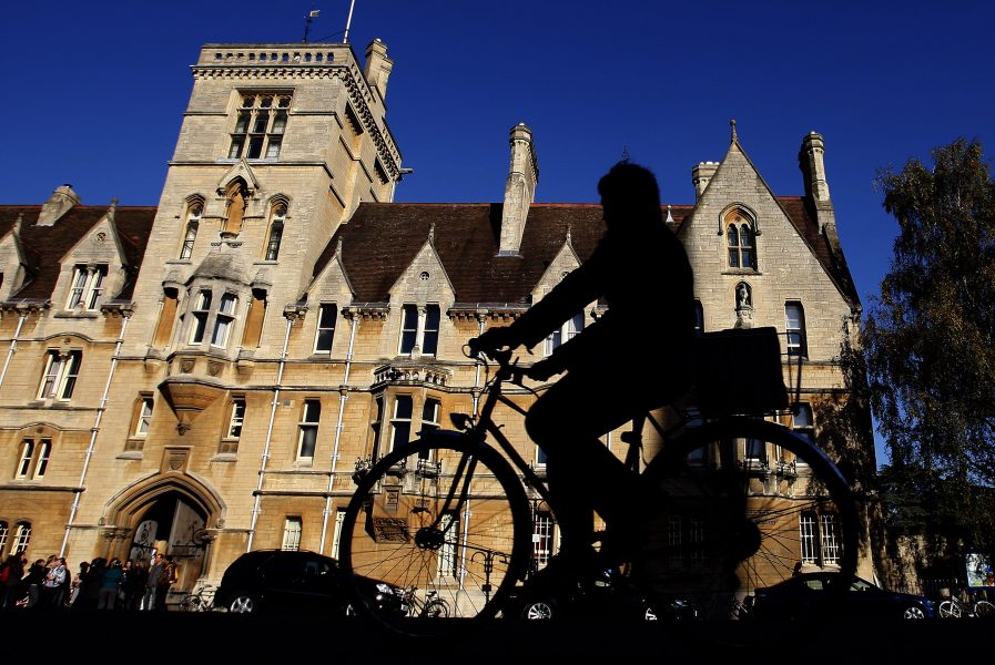 En cyklist framför en av oxforduniversitetets byggnader.