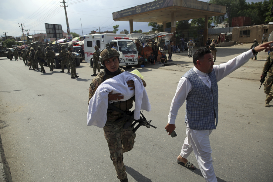 En afghansk soldat bär på ett barn efter att beväpnade män gått till anfall mot en förlossningsklinik i Kabul i tisdags.