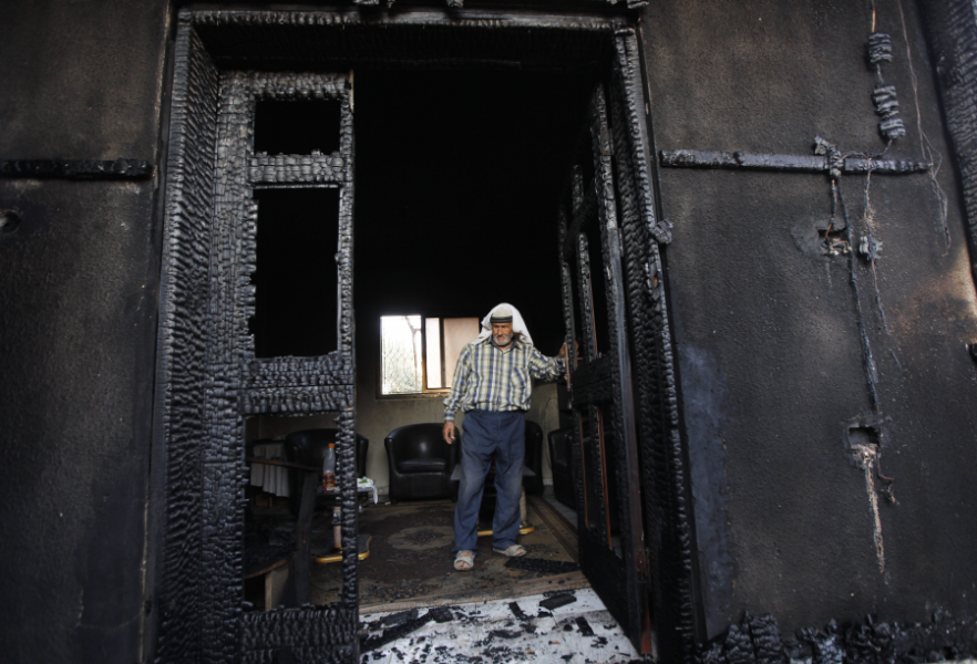 En man tittar på huset som brändes ned i attacken i juli 2015.