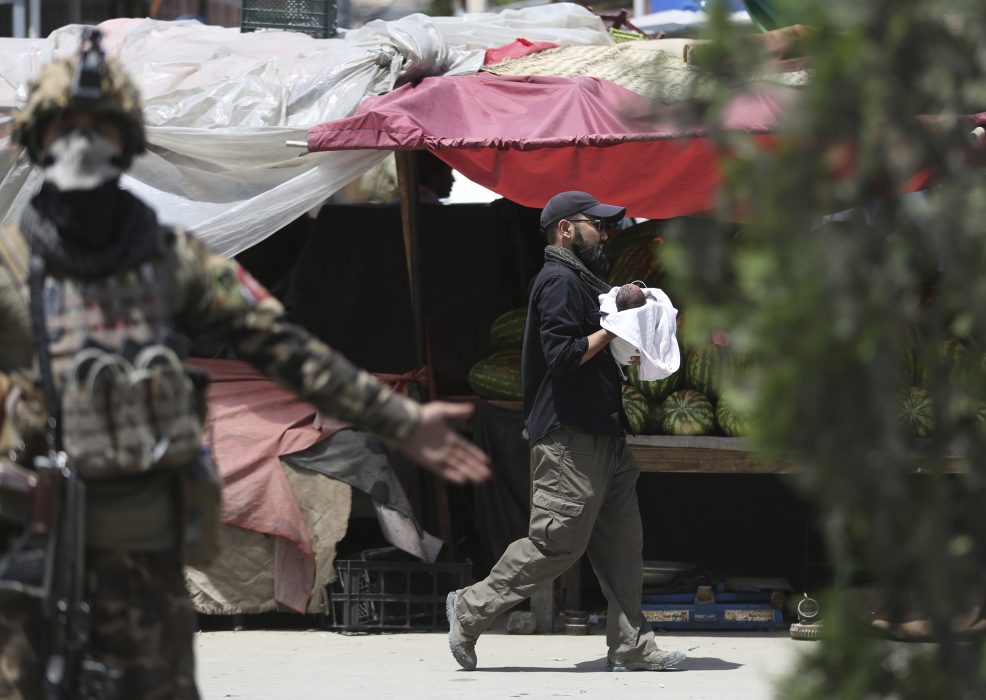 Afghansk säkerhetspersonal med ett spädbarn i famnen efter attacken mot en förlossningsklinik i Kabul den 12 maj i år.