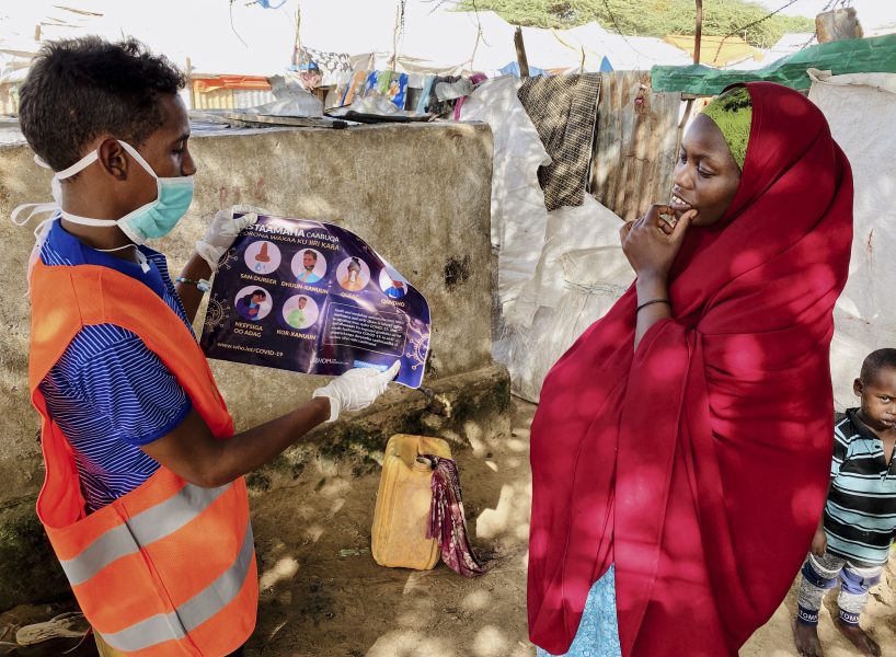 I ett läger utanför Mogadishu informeras en kvinna som är på flykt om hur hon kan skydda sig från coronasmitta.