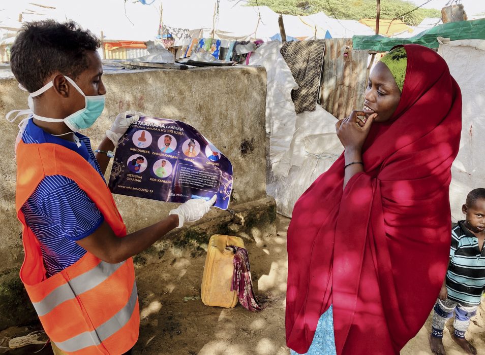 I ett läger utanför Mogadishu informeras en kvinna som är på flykt om hur hon kan skydda sig från coronasmitta.