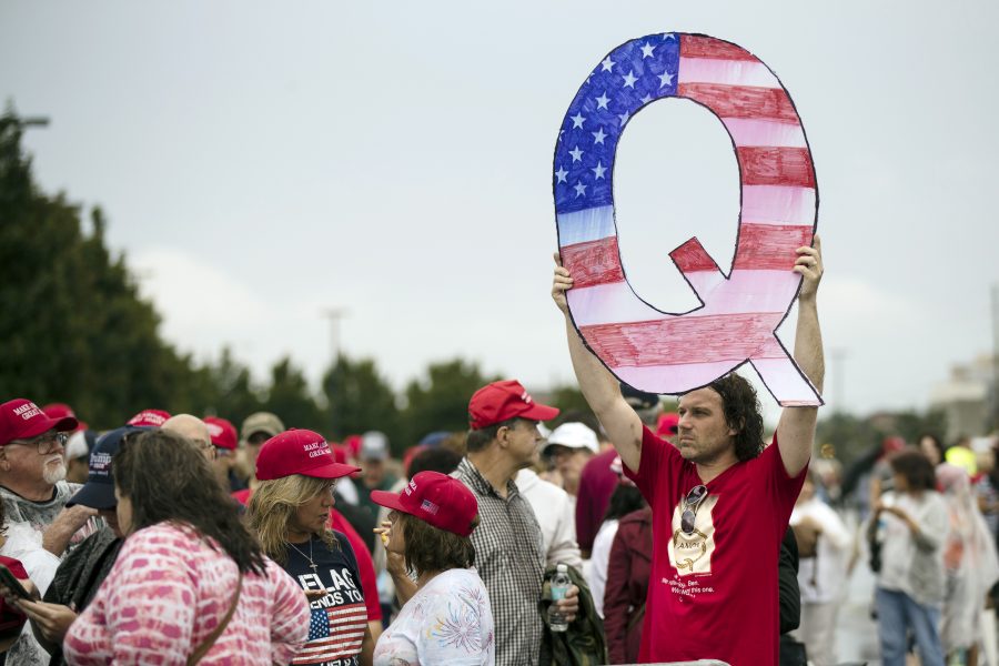 En man håller upp ett stort Q målat som en amerikansk flagga under ett av president Donald Trumps kampanjmöten i delstaten Pennsylvania i början av augusti.