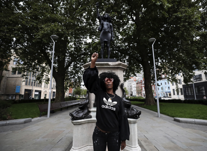 Black lives matter-demonstranten Jen Reid poserar framför statyn som hon stått modell för.