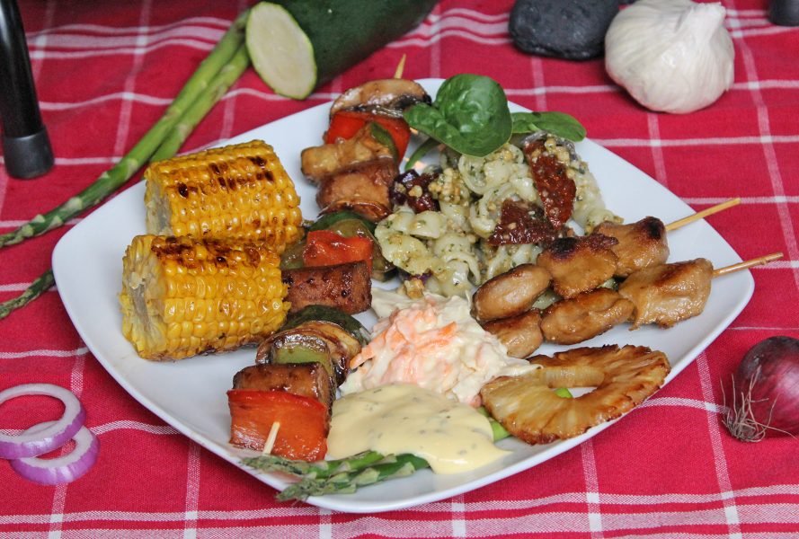 På grilltallriken finns pastasallad, tzayspett, grönsaksspett, färsk sparris med hollandaisesås, majskolv, coleslaw och grillad ananas.