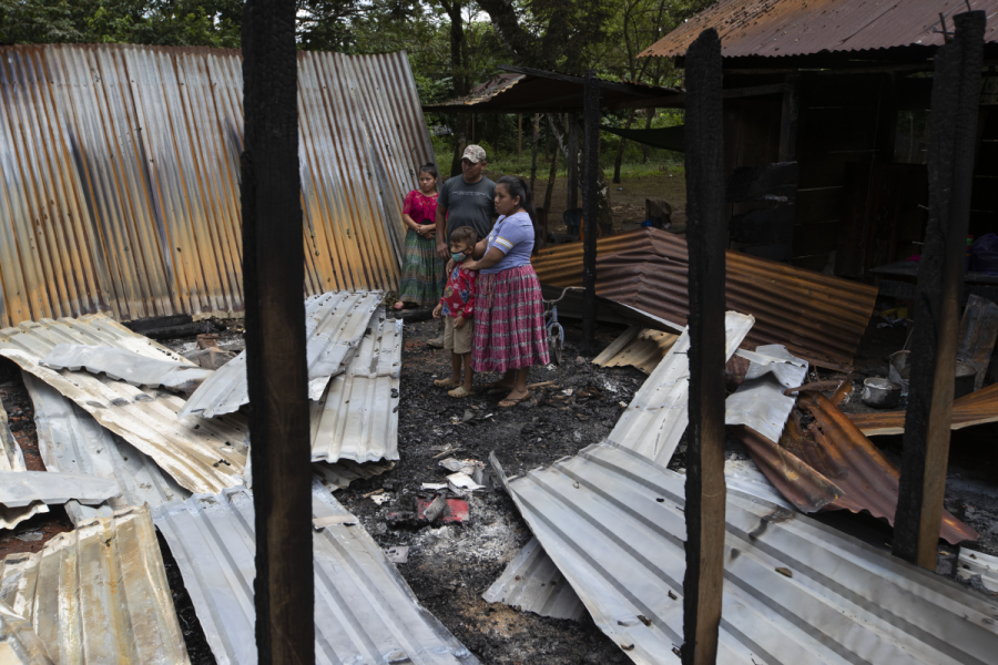 En av familjerna i byn Balbatzul står i resterna av sitt hem, som brändes ner av beväpnade gärningsmän i attacken tidigt i söndags.
