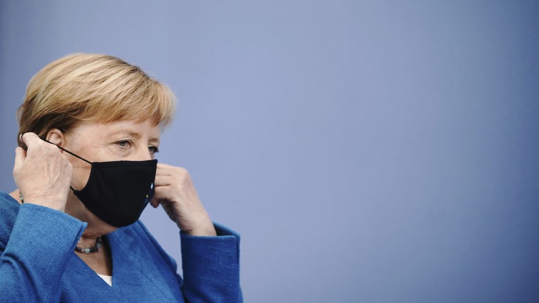 Tysklands förbundskansler Angela Merkel tar av sig sitt munskydd inför sin årliga sommarpresskonferens.
