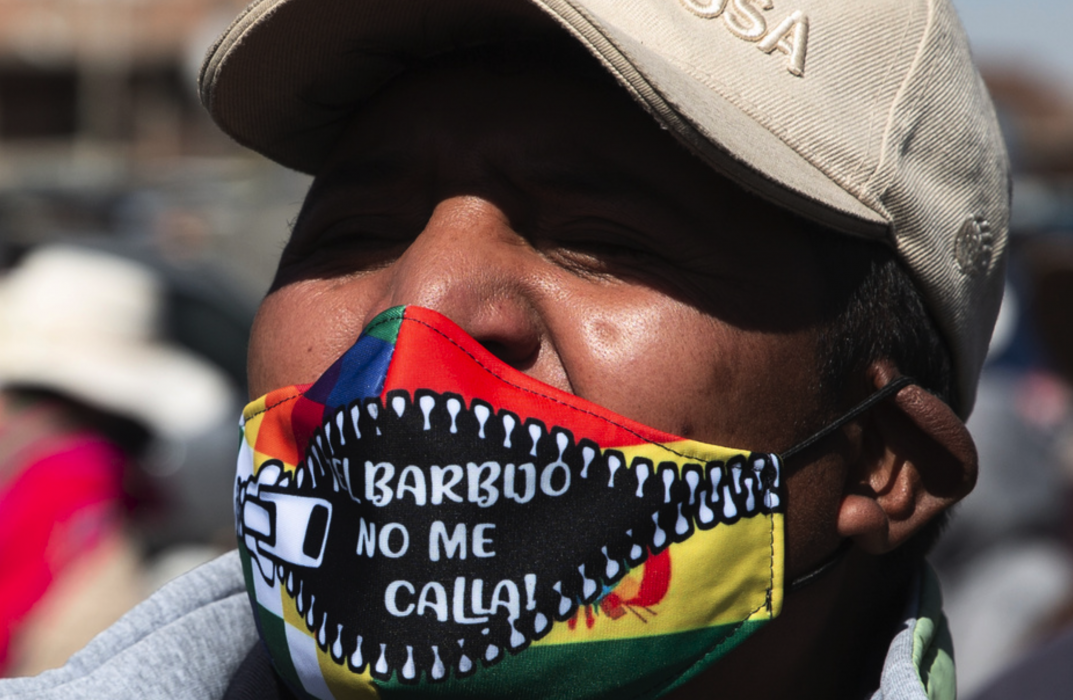 En demonstrant i El Alto bär en mask med texten "Masken tystar inte mig!" under en protest mot att valet skjutits upp igen.