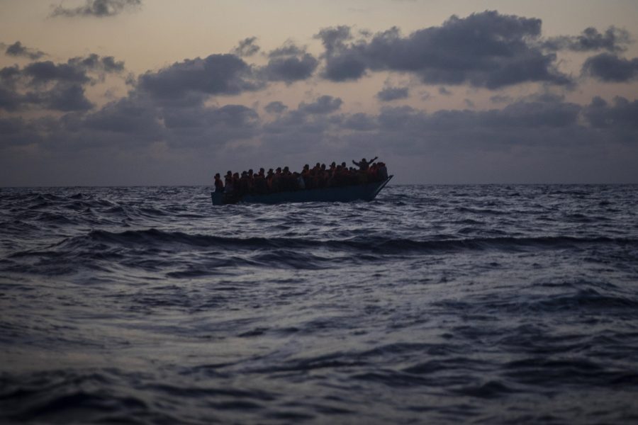 Afrikanska migranter väntar på assistans från spanska volontärarbetare, sedan de försökt korsa Medelhavet från Libyen i en ranglig trädbåt.