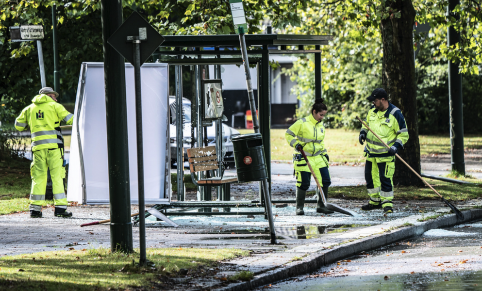 Personal från Malmö Stad röjer upp krossat glas från en vandaliserad busskur.