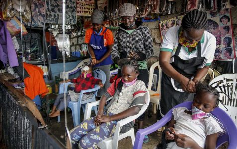 Smitttspridningen av Covid-19 och andra virus kan inte stoppas så länge fattiga tvingas ut och jobba för att överleva. Därför föreslår FN nu basinkomst. På bilden: Gettrueth Ambio, Jane Mbone, och Hamida Bashir, får håret stylat i samma form som nya coronaviruset, på salong Mama Brayo Beauty Salon i Kiberas slum slum i Nairobi, Kenya. Foto: Brian Inganga/AP/TT