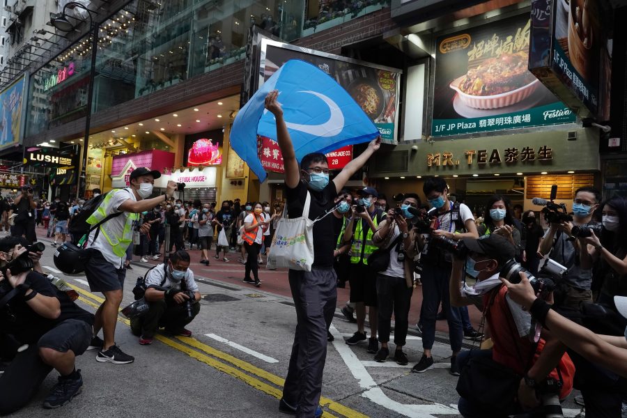 En demonstrant i Hongkong håller upp en uighurisk flagga under en protest .