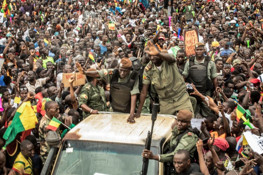 En representant för juntan i Mali vinkar från ett militärfordon medan supportrar firar att president Ibrahim Boubacar störtades i en militärkupp i augusti.