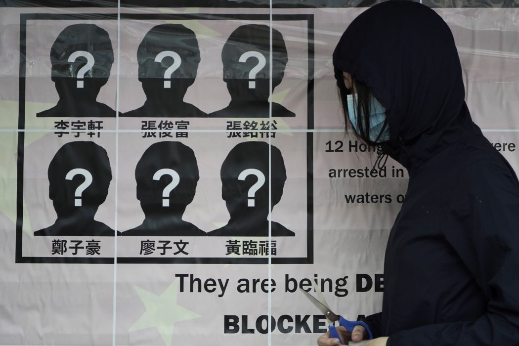 En universitetsstudent sätter upp en affisch som kräver att tolv aktivister som försökt fly från Hongkong släpps av Kinas myndigheter.